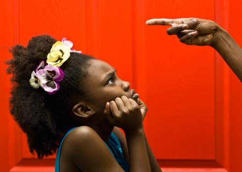 A young girl looks up worriedly at a pointing hand, capturing an 