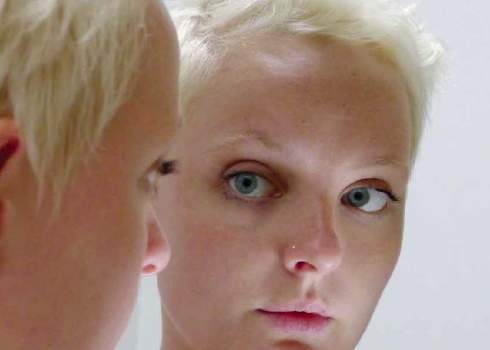 A woman looking at herself in the mirror.