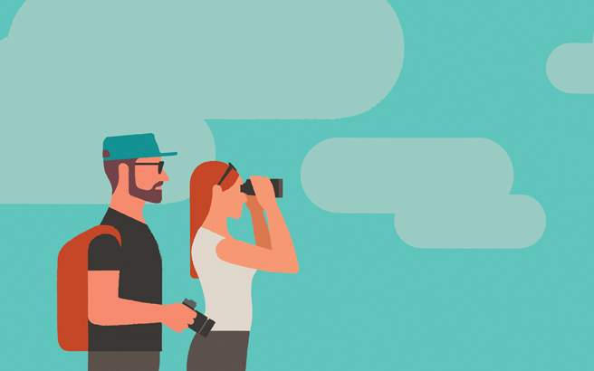 A hiker with a backpack looking through binoculars at the sky.