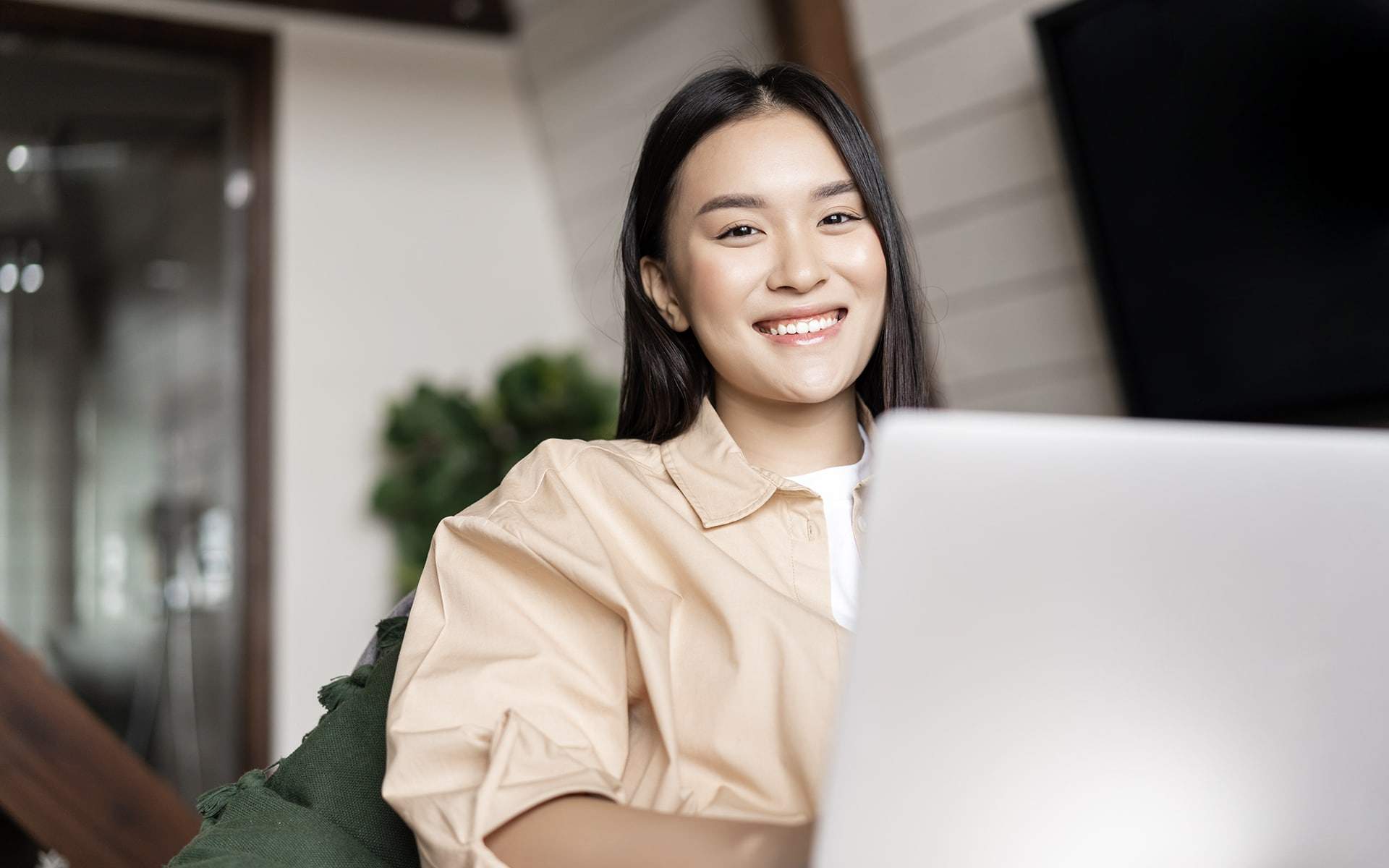 A smiling woman working on a laptop in an office setting.