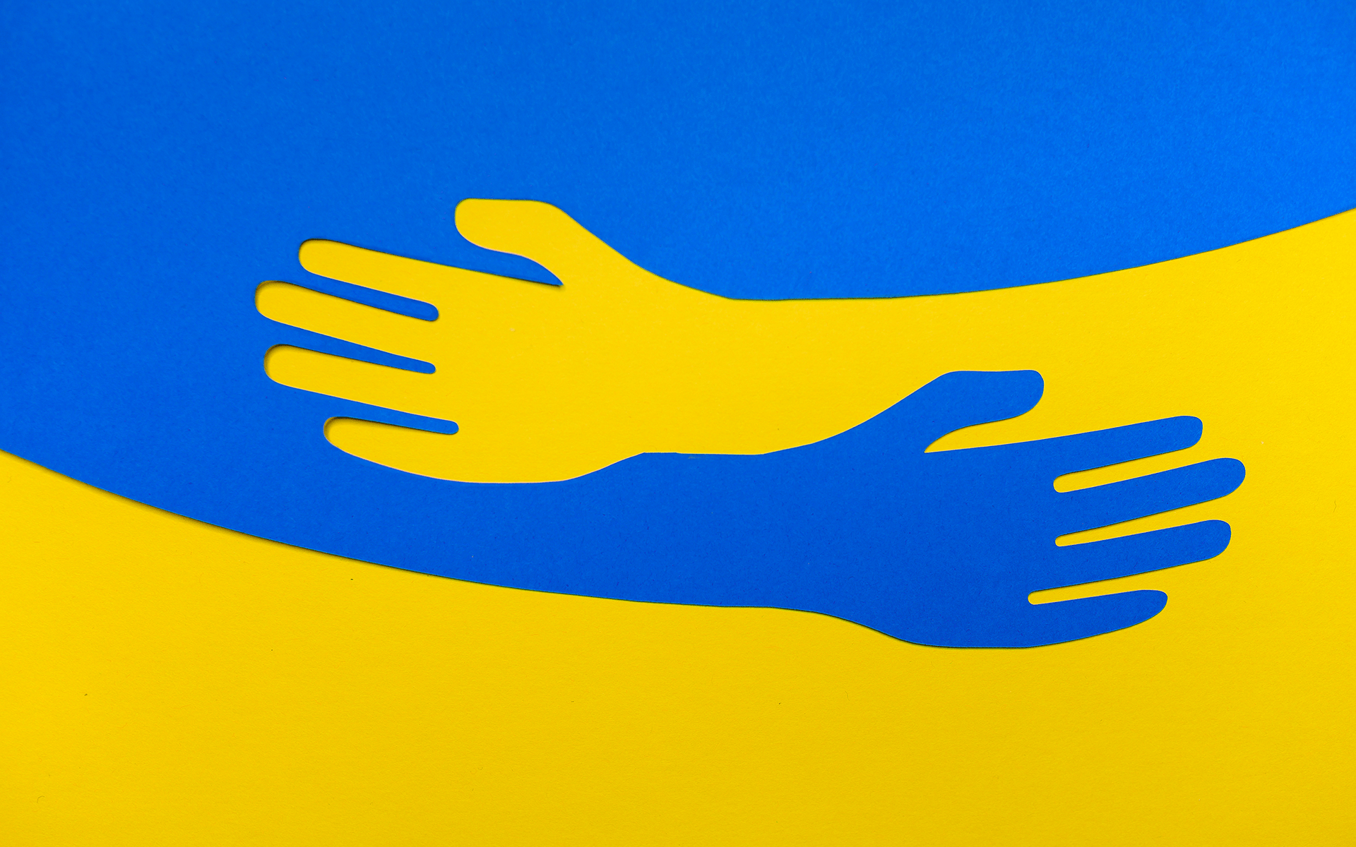 Image description: The top half of the image is blue and the bottom is yellow. From each colour comes a hand that reaches into the other color as if hugging.